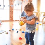 girl in blue denim dungaree pants holding blue and white polka dot handbag